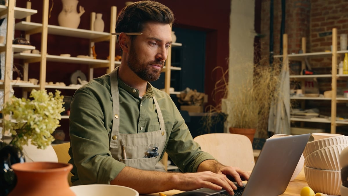 Small business owner running his shop with his website open on a laptop