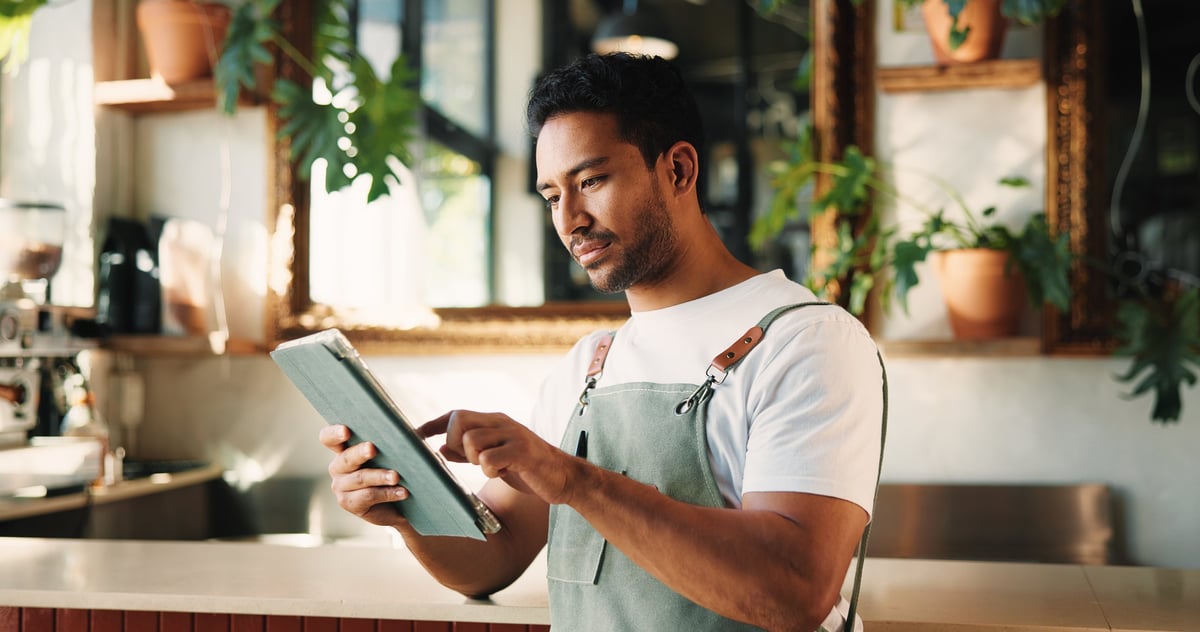 Café owner checking the menu and prices on a tablet